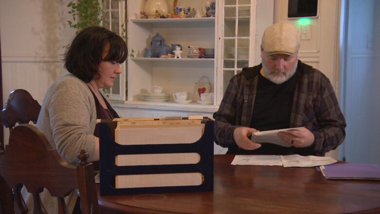 Two people sit at a table and look over documents.