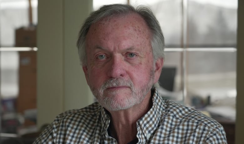 older man with grey hair looks at camera