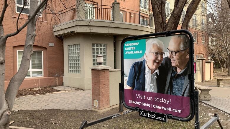 A sign outside a building depicts an older couple laughing and reads, 