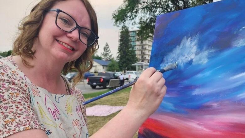 A woman painting at a canvas.