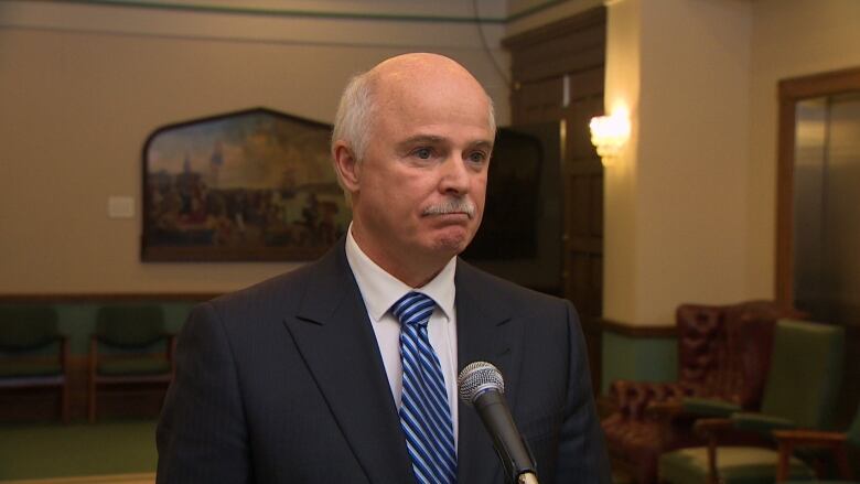 A man in a black suit standing in a government lobby. 