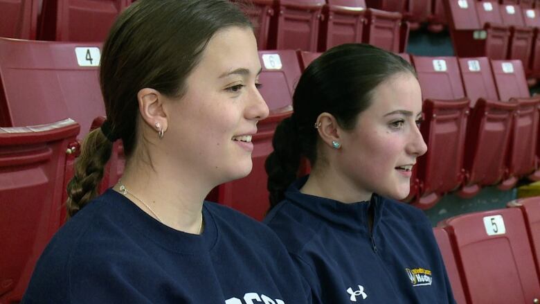 Two women sit on arena seats