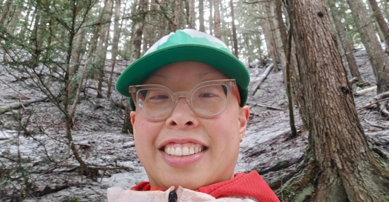 A woman takes a selfie while out for a walk in the woods.