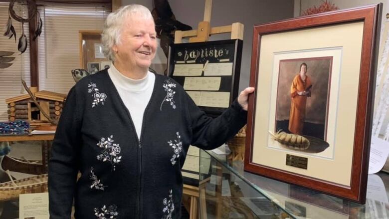 A woman in a museum holds a framed portrait.