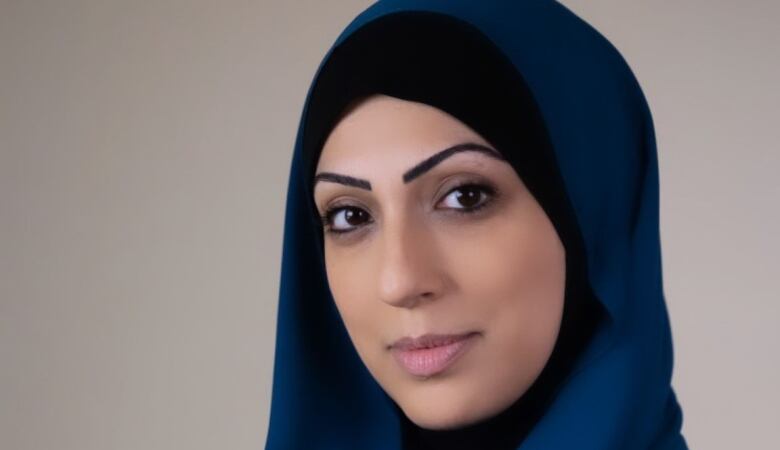  A woman in a blue hijab faces the camera. 