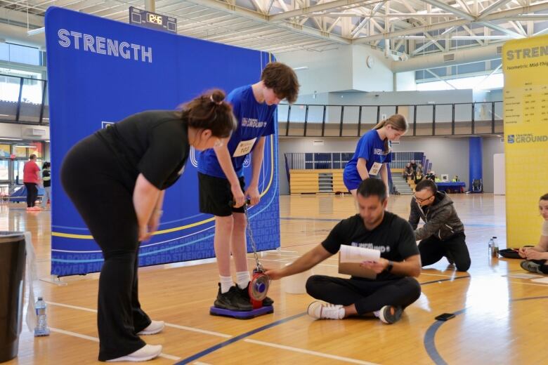 A young man tries to pull up a handle attached to a chain as part of the strength challenge. 