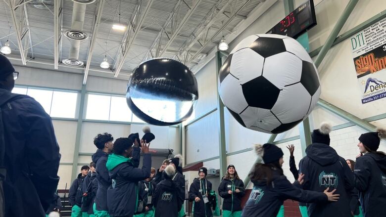 Kids in indoor gym playing with big beach balls