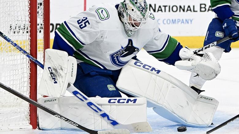 Vancouver Canucks goaltender looks down at a puck at the side of his crease in a March 07, 2024 NHL game in Las Vegas.