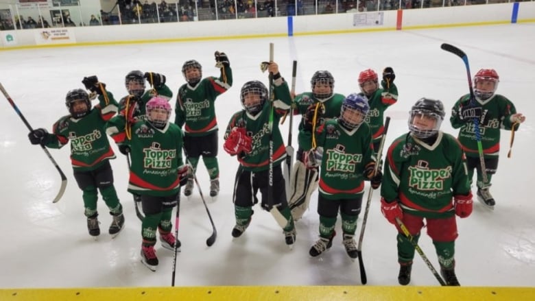 Some young hockey players celebrate on the ice 