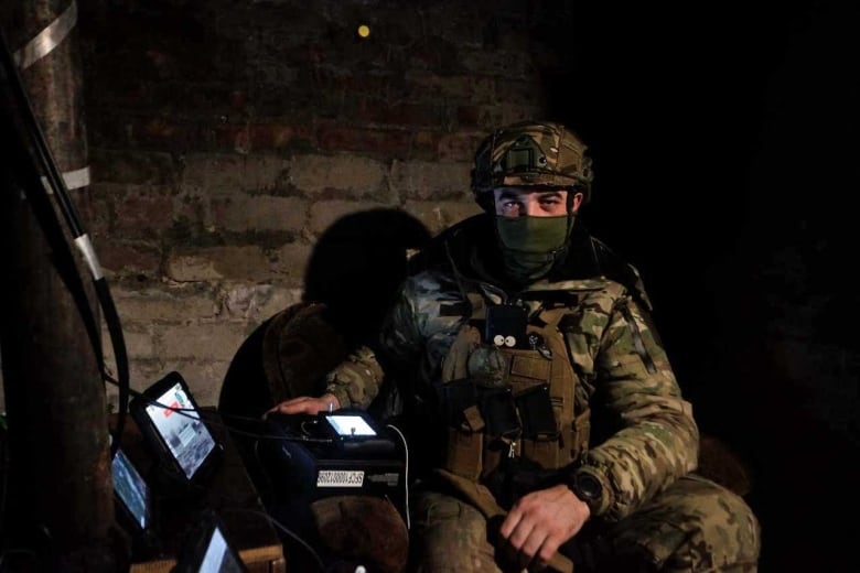 A Ukrainian drone operator with an array of tablets showing video feeds and satellite imagery.