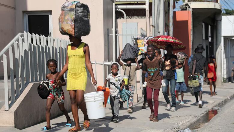 People walk in the street holding their belongings.