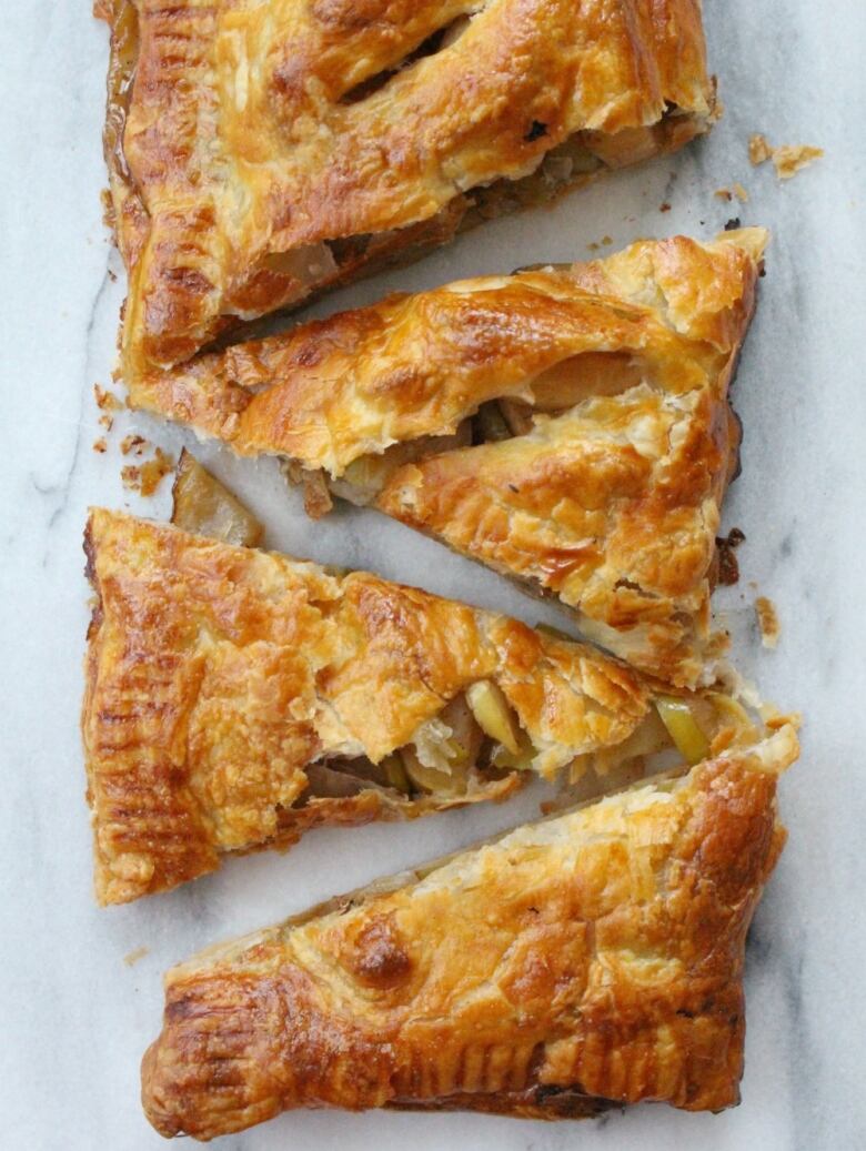 an apple pie cut into slices on a marble board.