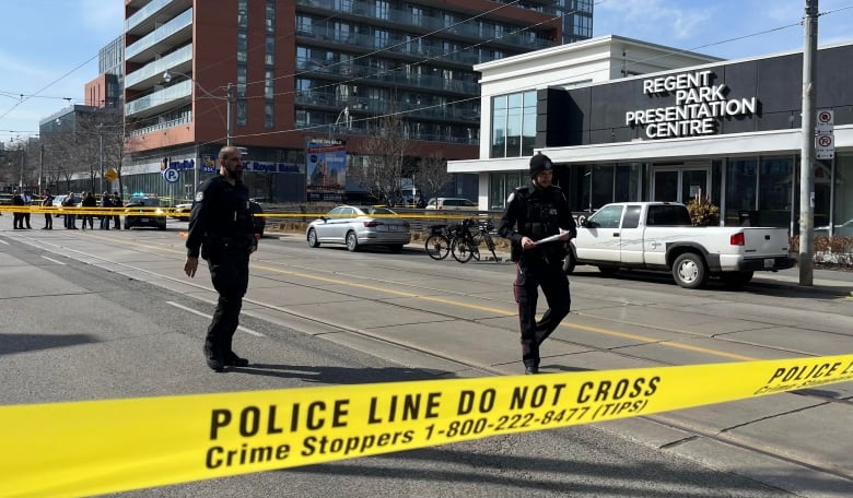 Photo of two police on the street surrounded by yellow tape reading 