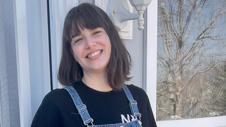 A woman in a denim dress and black hair, smiling.