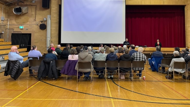 A group of people sitting in a gym in Regina for a meeting held by Government of Saskatchewan officials about the plans for a new complex needs emergency shelter.