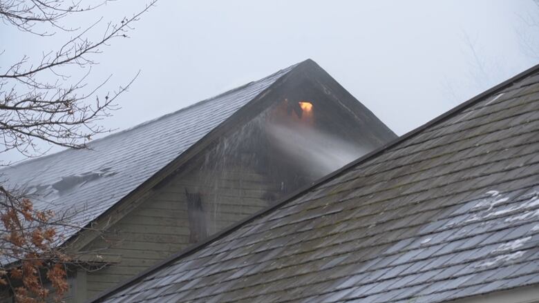 Flames can be seen inside a building as firefighters spray it with water.