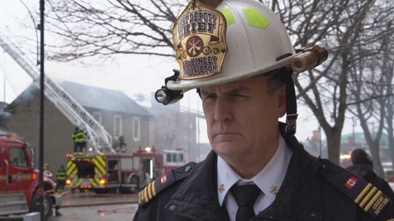 David McKinley speaks as firefighters work in the background to put out a fire in Fredericton.