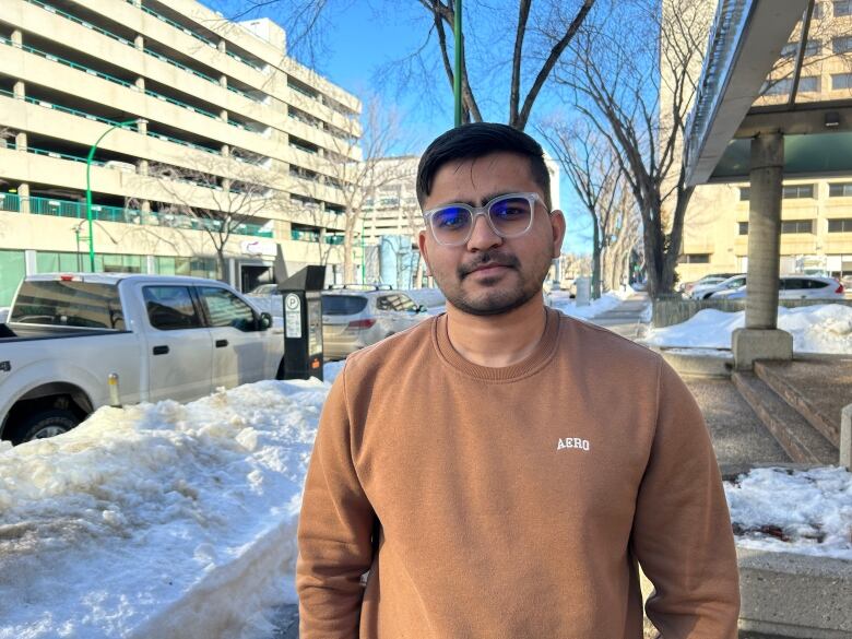 A spectacled young man in a brown vest.