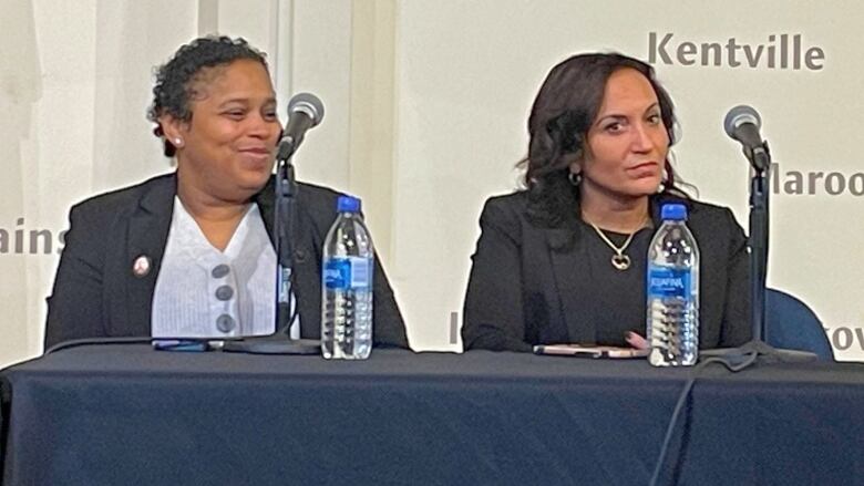 Two women sit next to each other at a table.