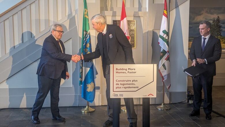 Two men shake hands behind a podium.