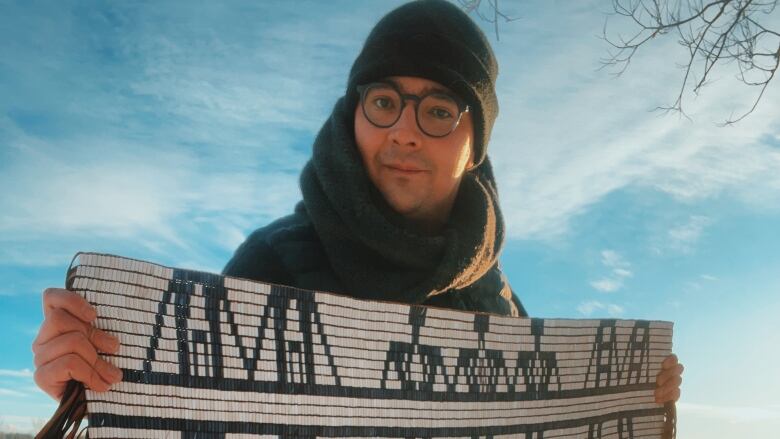 Man stands in snowy landscape with wampum belt.