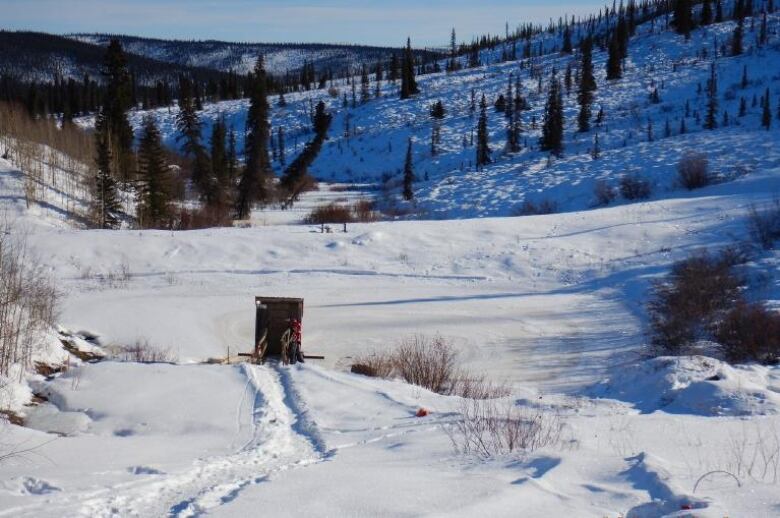 A frozen pond is seen in a snowy landscape.