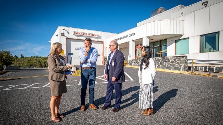 Four people stand outside of a hospital.