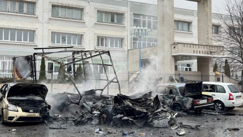 Smoke rises from cars destroyed in a missile attack.