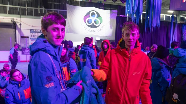 Two young people pause, holding a jacket between them