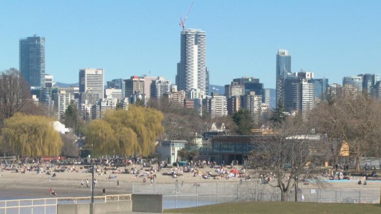 A packed beach wide shot with downtown behind it.