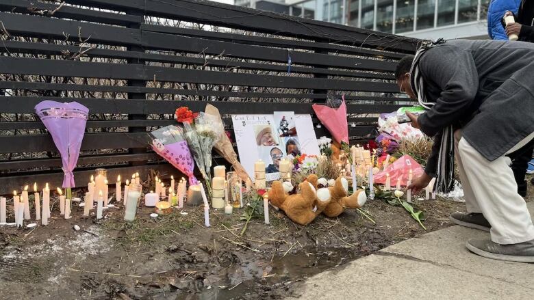 A person is seen adding to a makeshift memorial. 