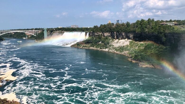 A rainbow stretches across the Niagara River. The Peace Bridge is visible in the background. 