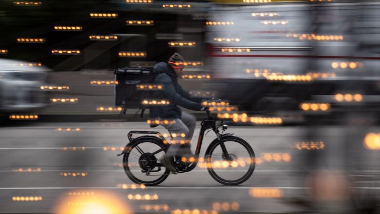 A man wearing a toque and a jacket rides a bicycle.