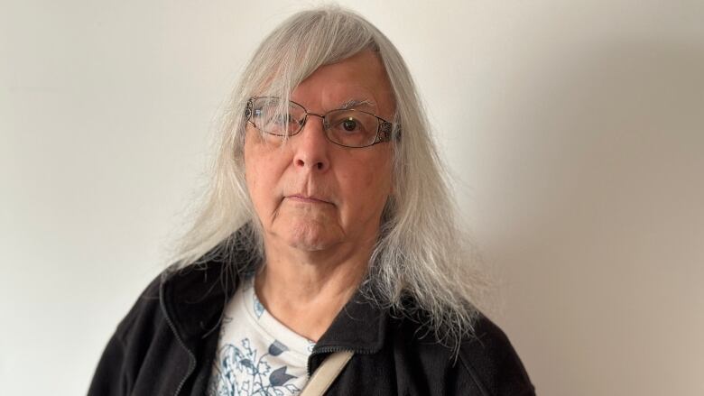 A woman with grey hair and glasses.