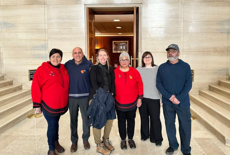 A group of six people stand inside a federal court house. 