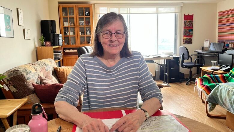 A woman sits at her kitchen table.