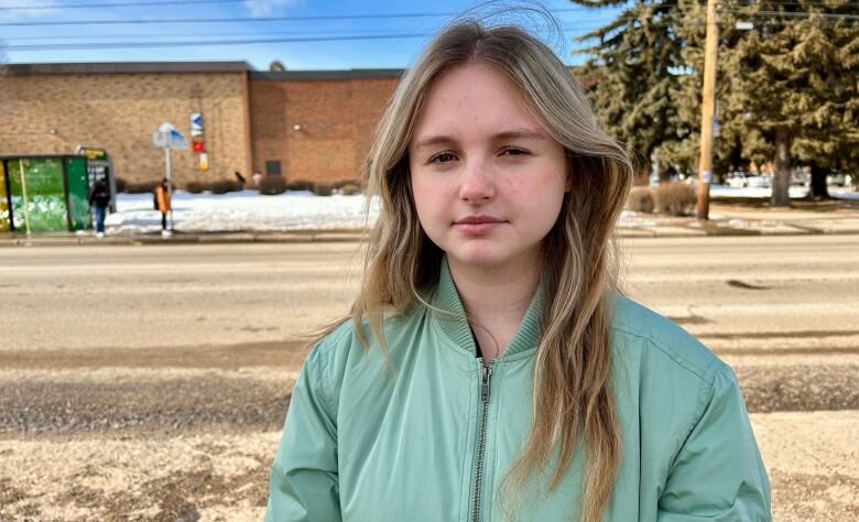 A young girl in a teal puffer jacket.