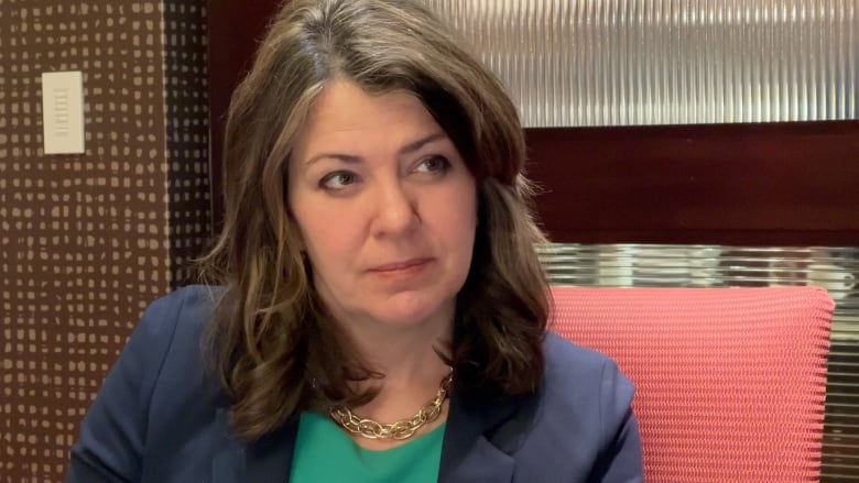 A woman sits in a chair at a hotel conference room.