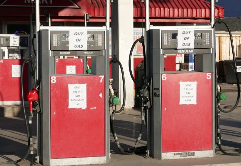 Two gas pumps are seen with signs that read 