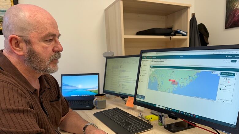 A man is shown in front of a computer screen which shows a Nova Scotia map.