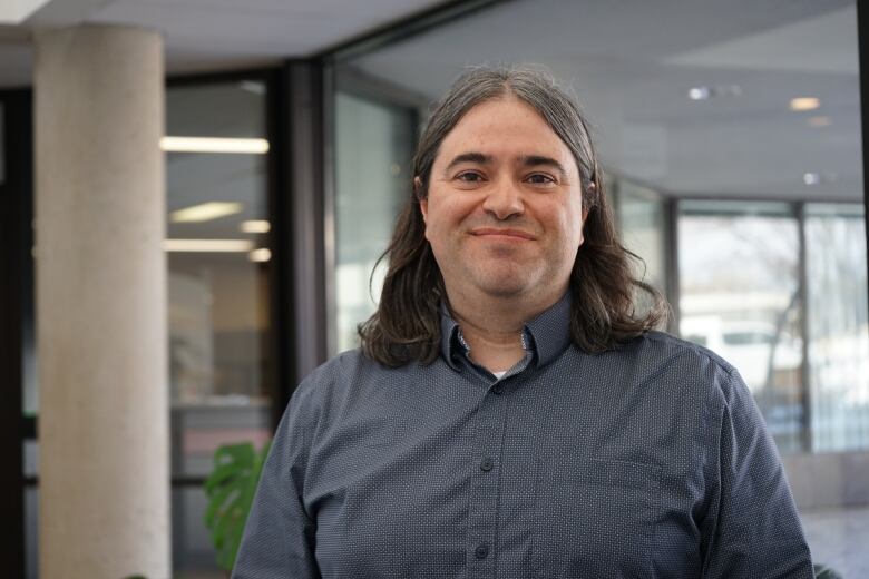 A man with long hair wearing a dress shirt.