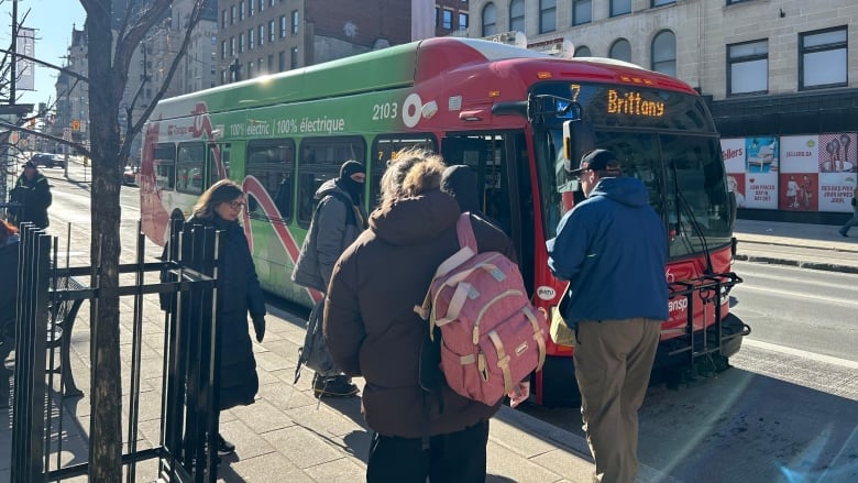 A red and white bus with green decor noting that it's an electric bus.