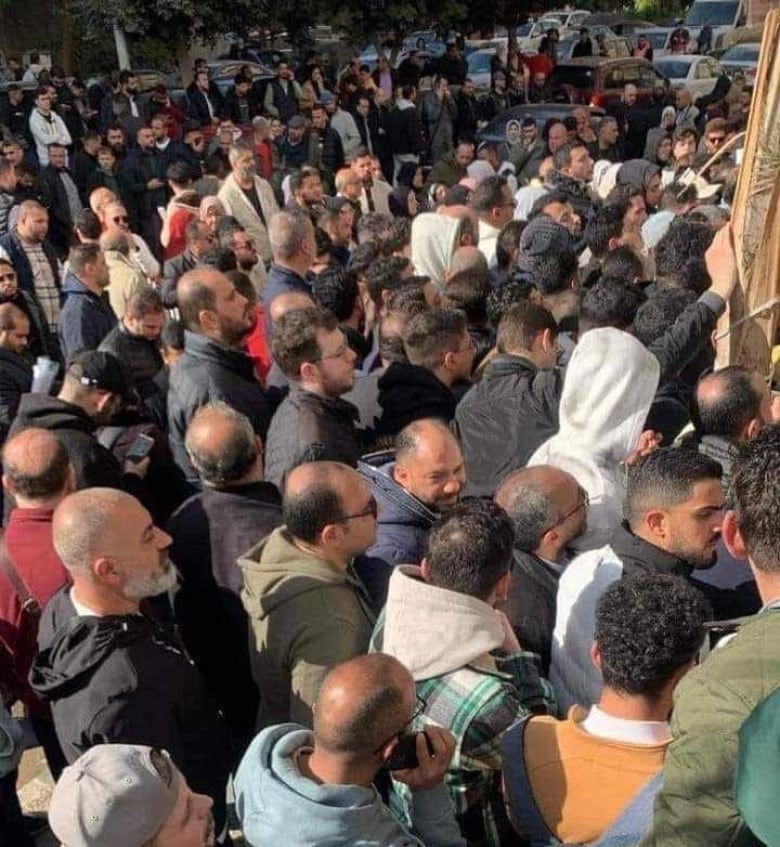 A crowd of people wait outside a building