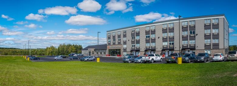 A four story hotel surrounded by green grass and a parking lot.