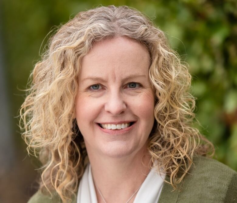 A woman with wavy blonde hair smiles at the camera.