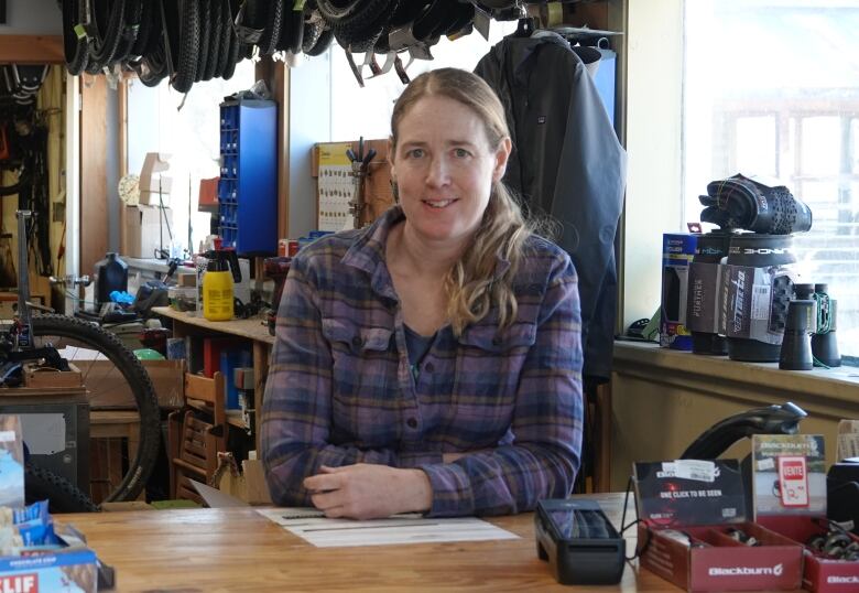 A woman poses behind the counter with bikes in the background