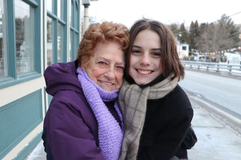 A woman smiles at the camera, wrapping her arms around her grandson.