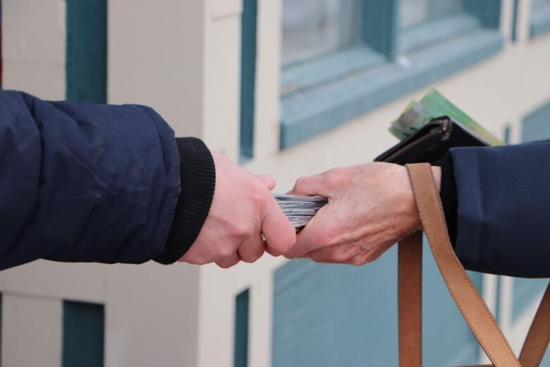 A picture of someone handing off several eclipse glasses into someone elses hands 