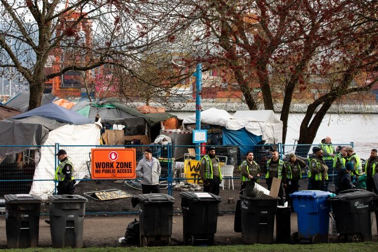 Vancouver Police officers are pictured near fencing put up around Crab Park during tent removals in Vancouver, B.C on Monday March 25, 2024.