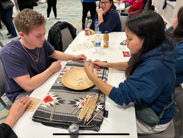 two youth playing a game with a bowl and dice.